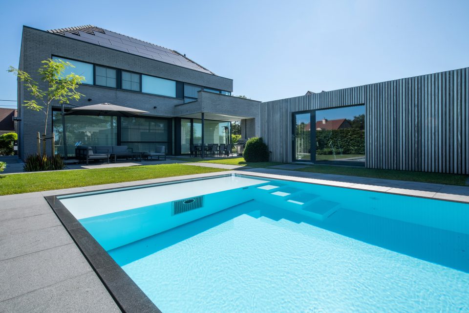Hellblaues Schwimmbecken mit integrierter Gegenstromanlage (Jet-Düse), versetzten Einstiegsstufen und dunkler Beckenumrandung.